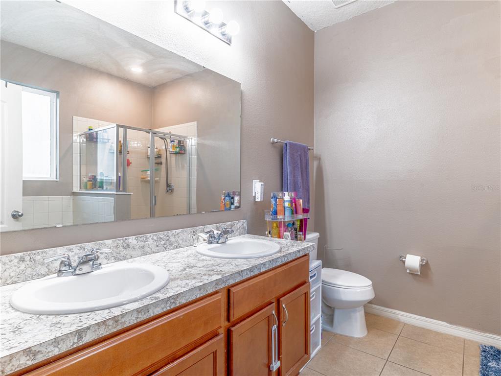 4504 Orchard Grove Road St. Cloud, FL 34772 - Photo 19 of 29 a bathroom with a granite countertop toilet sink and mirror