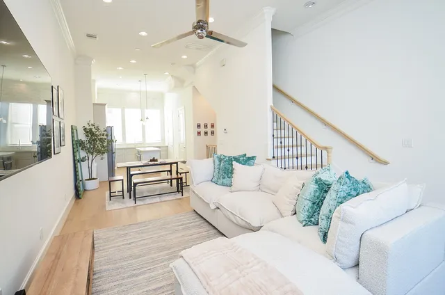 a living room with couches and a dining table with wooden floor