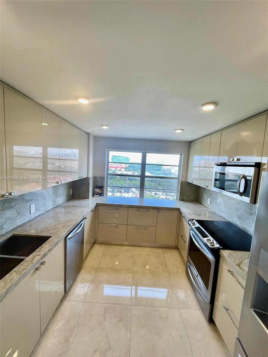 2851 Northeast 183rd Street, Unit 802E Aventura, FL 33160 - Photo 10 of 37 a kitchen with stainless steel appliances granite countertop a sink and stove top oven
