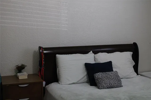 a bed sitting in a bedroom next to a window with a lamp and a potted plant on it