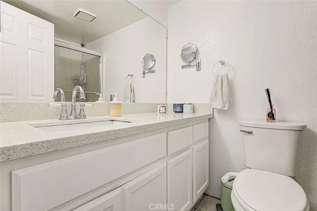 a bathroom with a granite countertop sink a toilet and shower