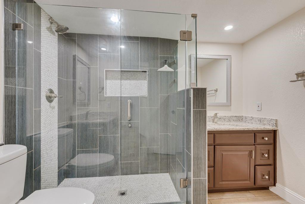 219 West Rochelle Road Irving, TX 75062 - Photo 18 of 29 Walk-in shower featuring gray subway tile, glass enclosure, and mosaic tile accents