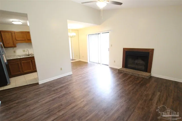 an empty room with wooden floor a fireplace and windows