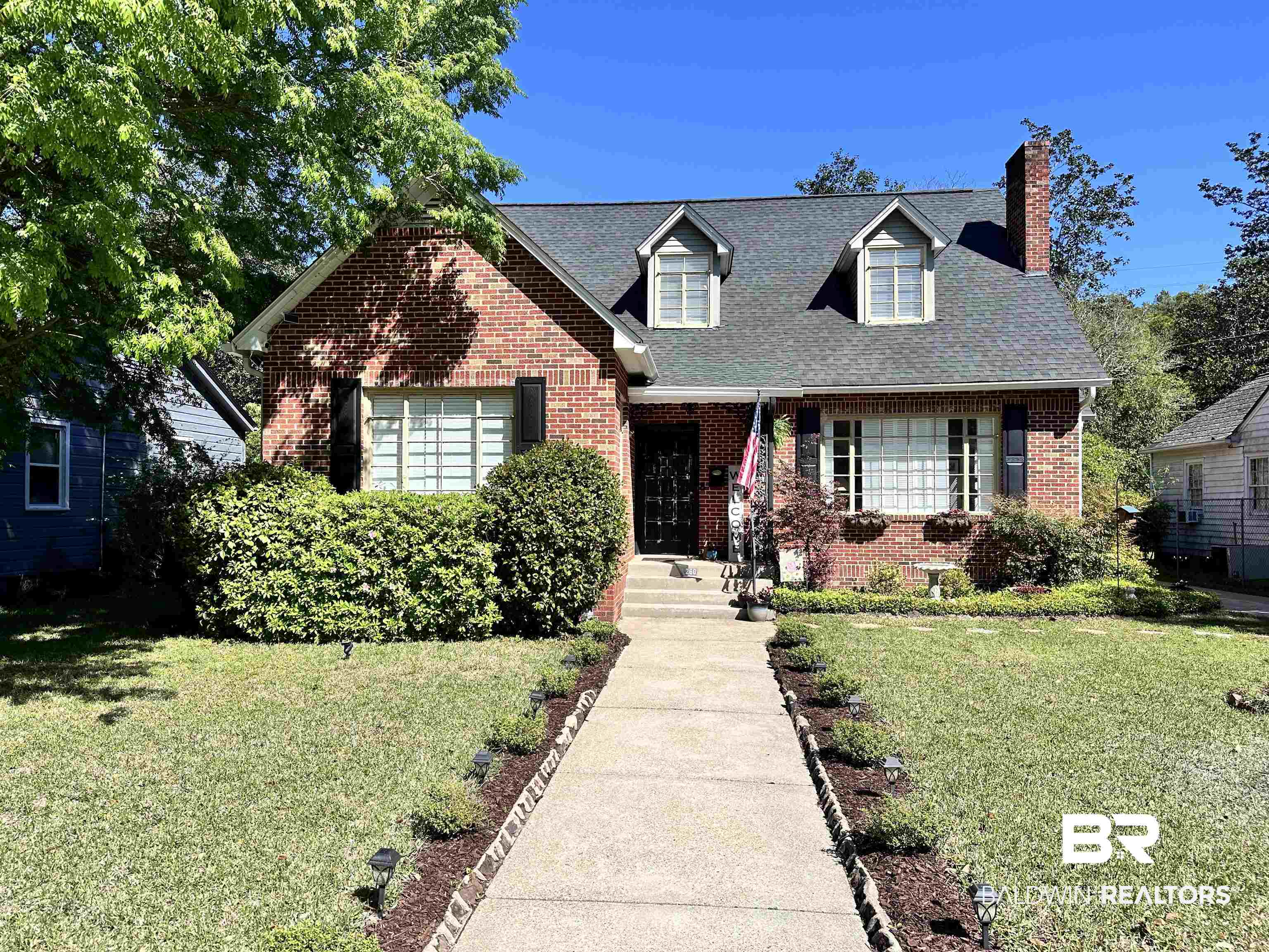 260 Siena Vista Street Mobile, AL 36607 - Photo 1 of 41 Cape cod house featuring brick siding, a chimney, a front lawn, and a shingled roof