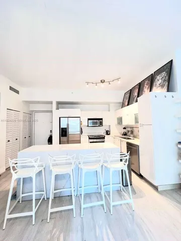 a kitchen with a table chairs refrigerator and wooden floor