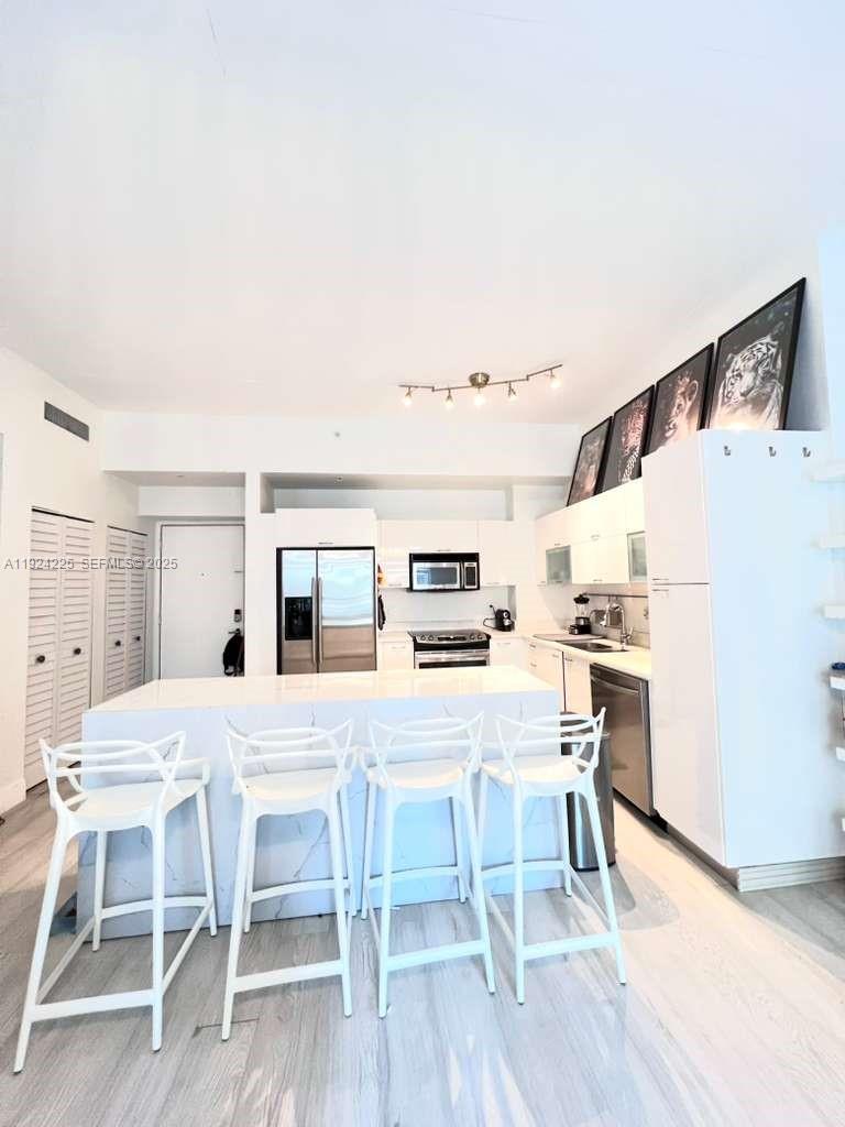 133 Northeast 2nd Avenue, Unit 208 Miami, FL 33132 - Photo 3 of 22 a kitchen with a table chairs refrigerator and wooden floor