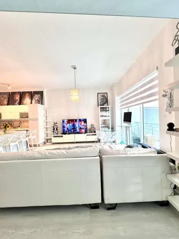 a living room with stainless steel appliances kitchen island granite countertop furniture and a large window