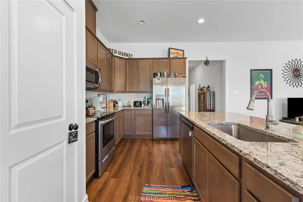 a kitchen with granite countertop a sink a counter top space stainless steel appliances and cabinets