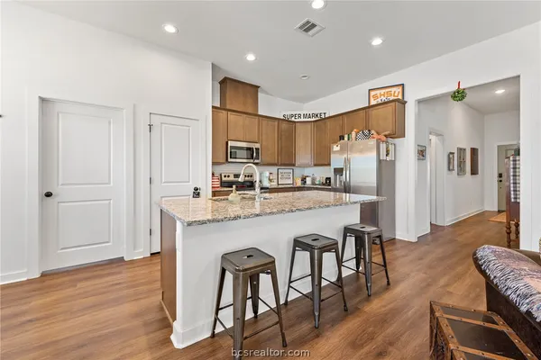 a kitchen with stainless steel appliances granite countertop a refrigerator and a stove top oven