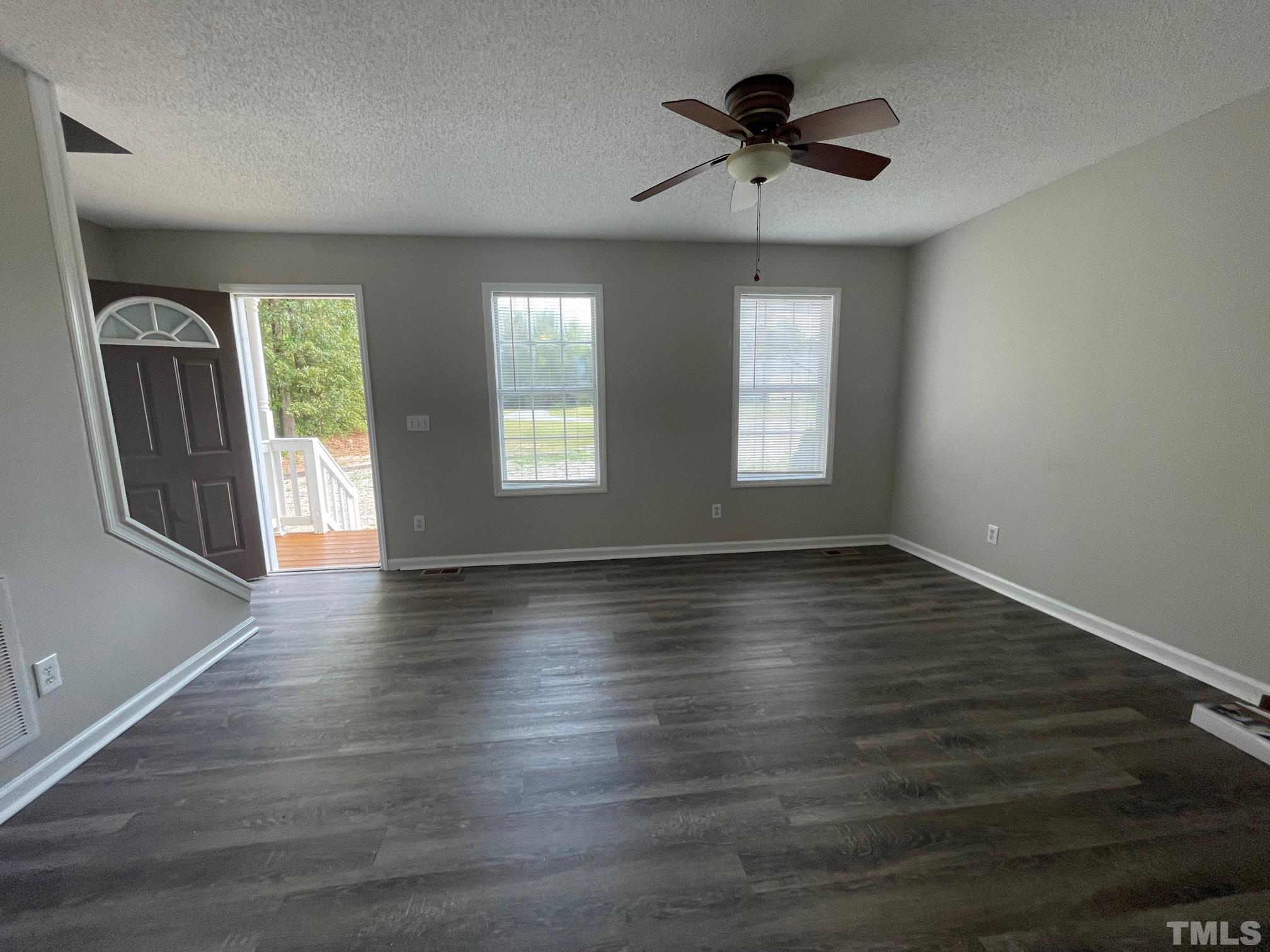 231 Smith Drive Angier, NC 27501 - Photo 3 of 19 an empty room with wooden floor chandelier fan and windows