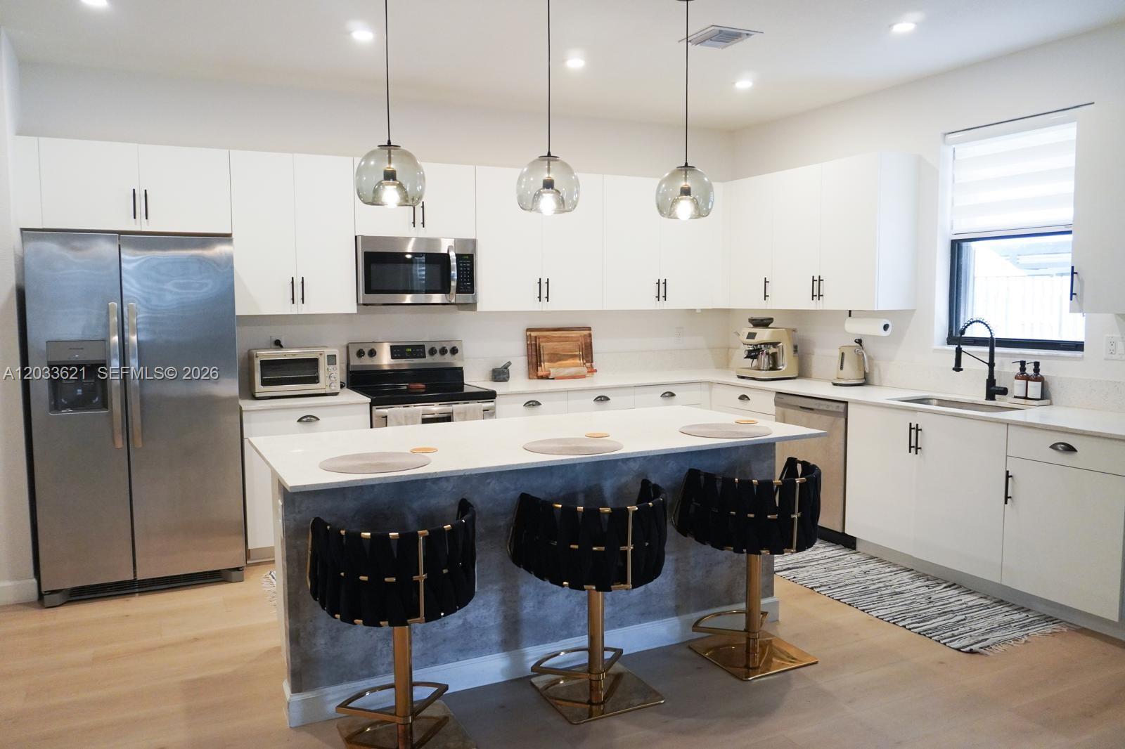 11942 Southwest 243rd Street Homestead, FL 33032 - Photo 10 of 50 a kitchen with stainless steel appliances a sink a stove a refrigerator cabinets and a dining table