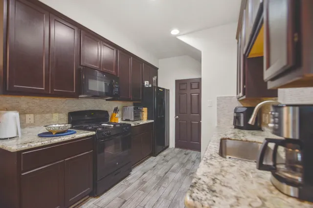 a kitchen with granite countertop wooden cabinets stainless steel appliances and a sink