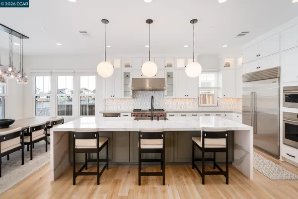 a kitchen with stainless steel appliances granite countertop a table chairs and a chandelier