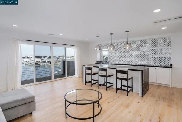 a room with stainless steel appliances kitchen island granite countertop a table chairs in it and wooden floors