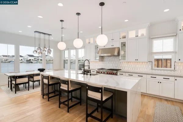 a kitchen with stainless steel appliances granite countertop a stove a sink dishwasher a microwave oven a stove and white cabinets with wooden floor