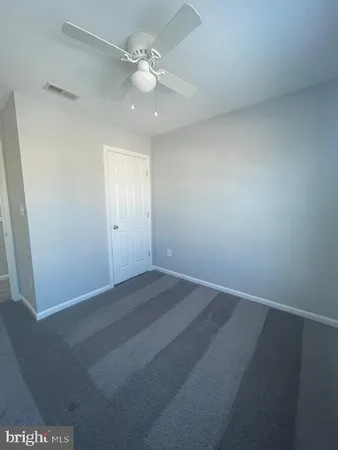 an empty room with a chandelier fan and windows