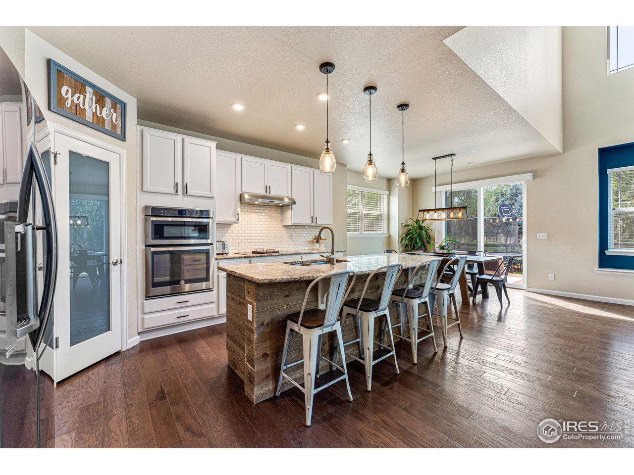 1908 Pioneer Circle Lafayette, CO 80026 - Photo 5 of 40 a open kitchen with stainless steel appliances granite countertop a stove a refrigerator a sink a dining table and chairs with wooden floor