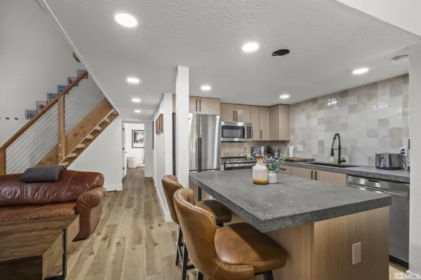 a kitchen with stainless steel appliances granite countertop a kitchen island a stove a table and chairs