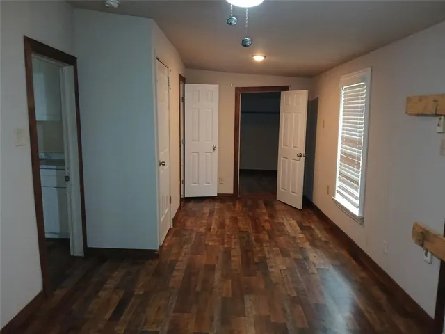 a view of hallway with window and wooden floor