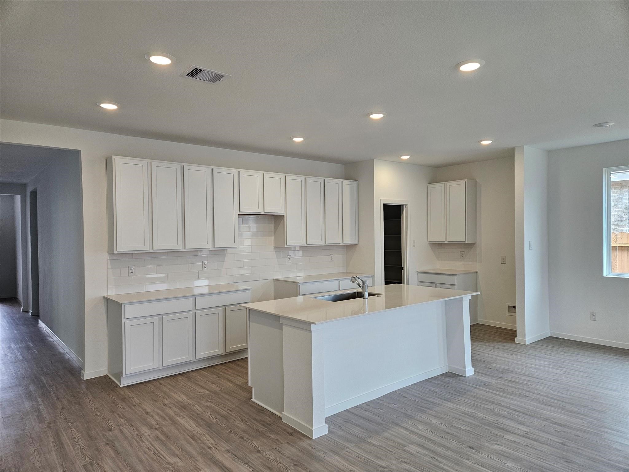 7750 Montana Ruby Drive Rosharon, TX 77583 - Photo 4 of 31 a kitchen with stainless steel appliances granite countertop a sink a stove a refrigerator and white cabinets with wooden floor