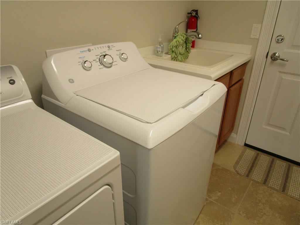 8677 Erice Court Naples, FL 34114 - Photo 12 of 42 Laundry area with washing machine and dryer, a sink, laundry area, and light tile patterned floors