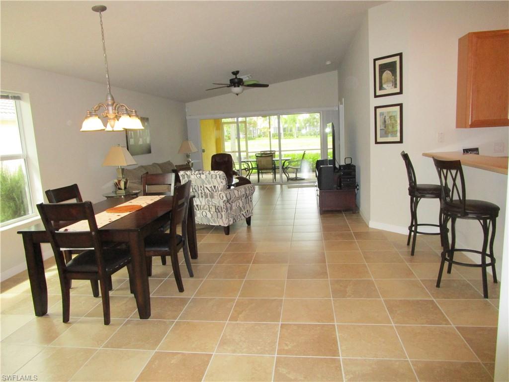 8677 Erice Court Naples, FL 34114 - Photo 39 of 42 a view of a dining room and livingroom with furniture wooden floor a rug a fireplace and a large window
