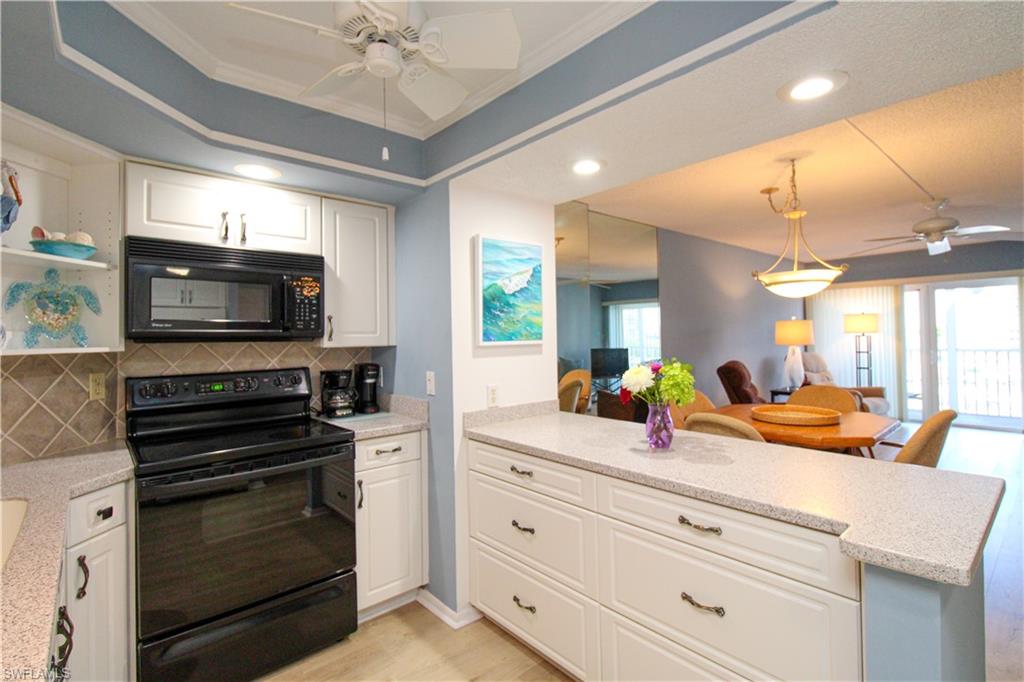 1 Bluebill Avenue, Unit 501 Naples, FL 34108 - Photo 37 of 38 a kitchen with stove a microwave and cabinets