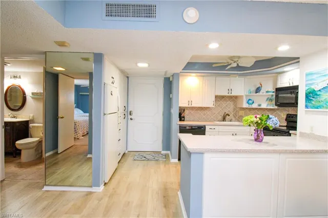 a kitchen with white cabinets and refrigerator