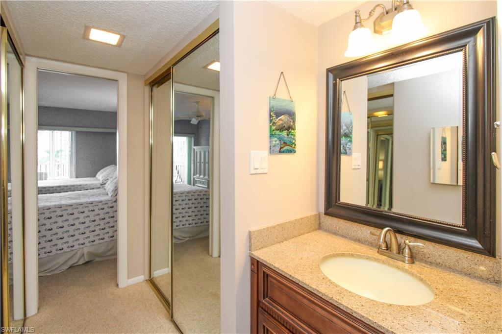 1 Bluebill Avenue, Unit 501 Naples, FL 34108 - Photo 22 of 38 a bathroom with a granite countertop sink vanity and mirror