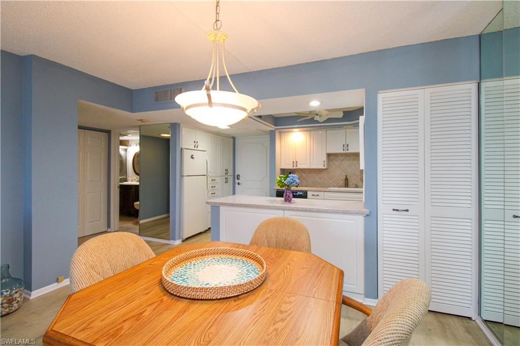 1 Bluebill Avenue, Unit 501 Naples, FL 34108 - Photo 10 of 38 a kitchen with stainless steel appliances granite countertop a sink a stove a dining table and chairs with wooden floor