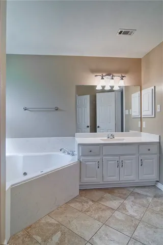 a spacious bathroom with a tub a double vanity sink and mirror