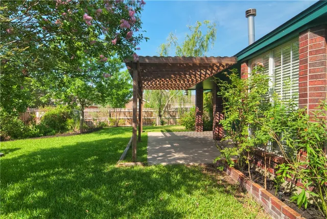a backyard of a house with table and chairs under an umbrella