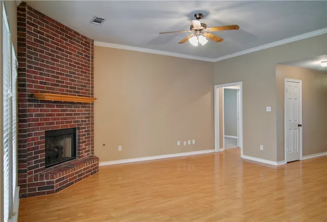 a view of an empty room with chandelier fan and fire place