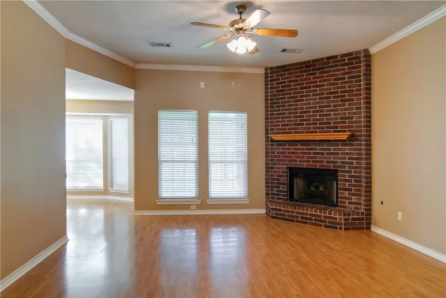 a view of an empty room with wooden floor fireplace and a window