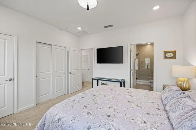 a bedroom with a bed and a flat tv screen on wall