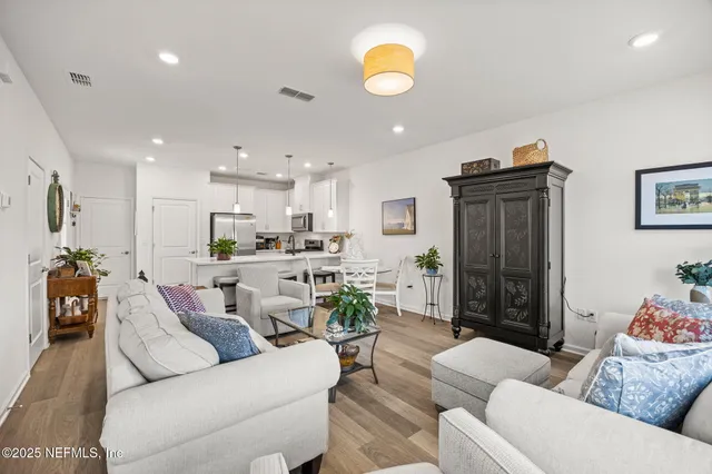 a living room with furniture kitchen view and a chandelier
