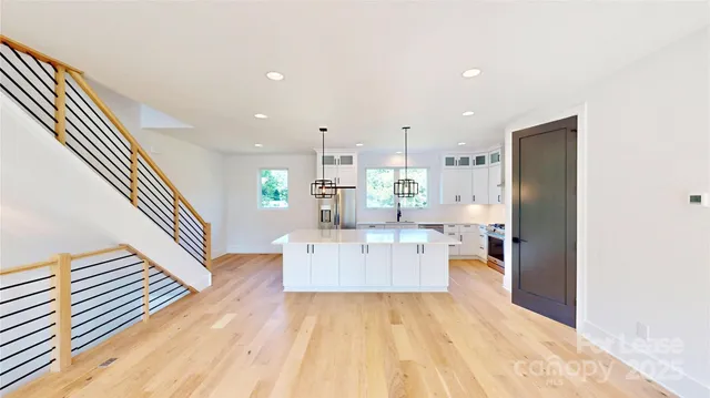 a large kitchen with kitchen island white cabinets and stainless steel appliances