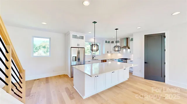 a large kitchen with stainless steel appliances granite countertop a stove and white cabinets with wooden floor