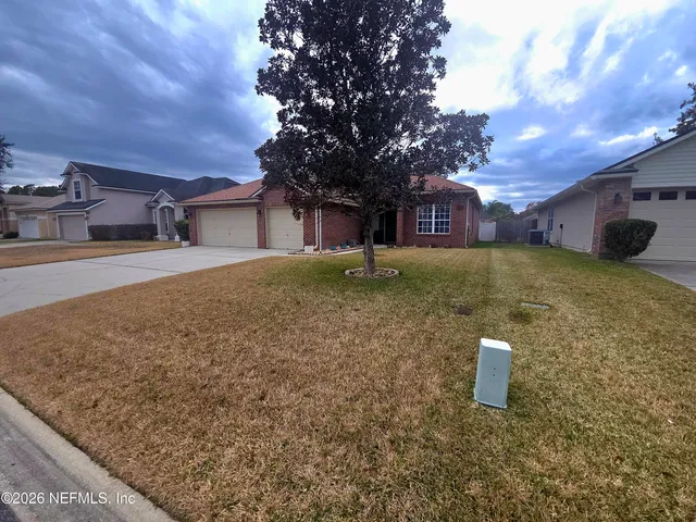 a view of a house with a yard and large tree