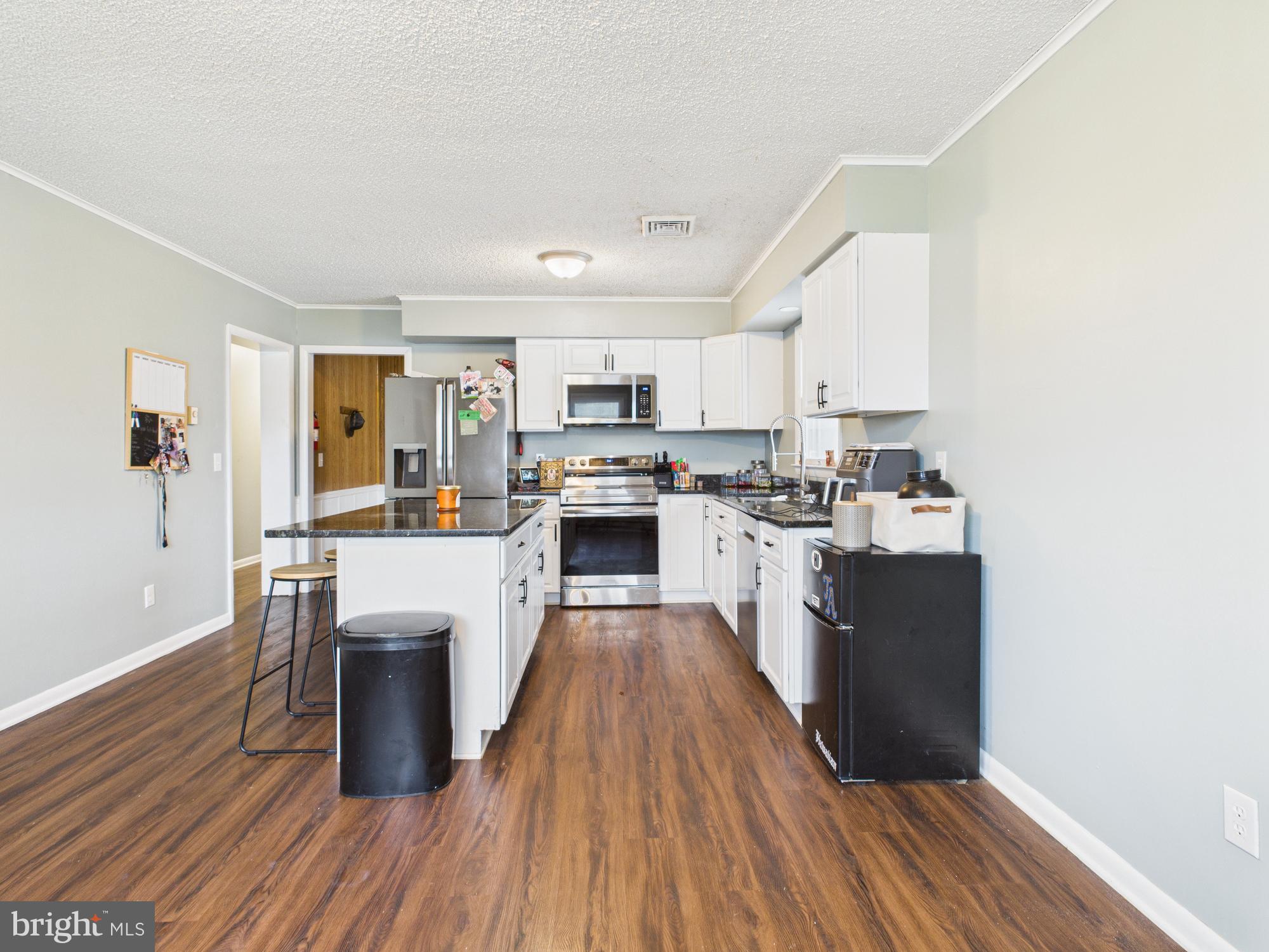 38 South Carter Road Smyrna, DE 19977 - Photo 25 of 30 a kitchen with stainless steel appliances granite countertop a stove top oven a sink dishwasher and a refrigerator with wooden floor