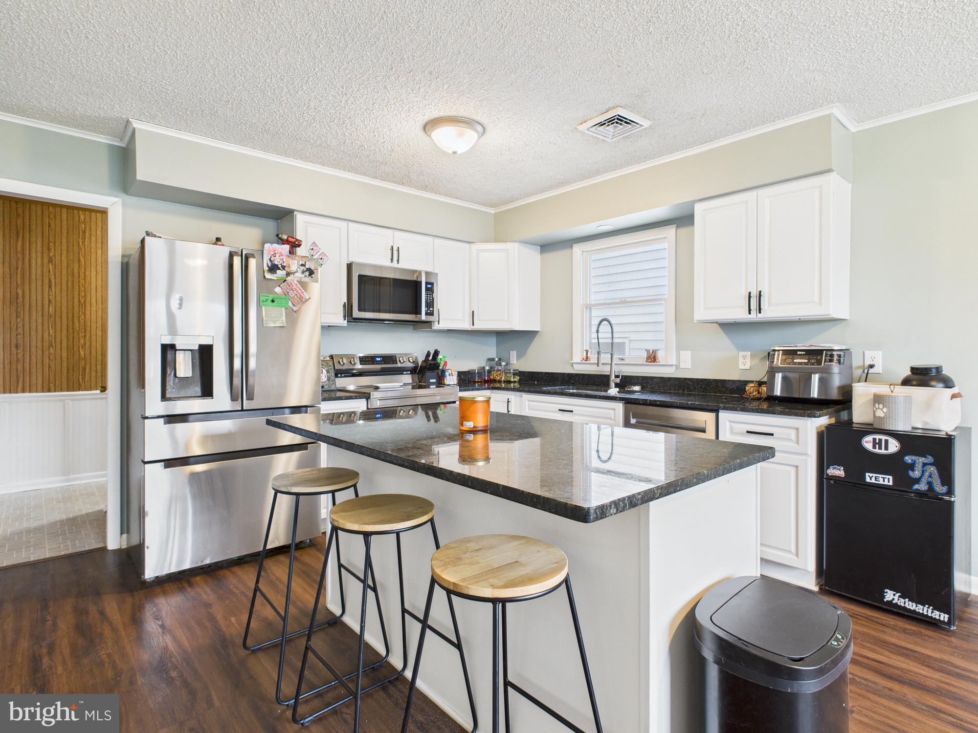 38 South Carter Road Smyrna, DE 19977 - Photo 26 of 30 a kitchen with stainless steel appliances granite countertop a stove top oven a sink a refrigerator a dining table and chairs with wooden floor