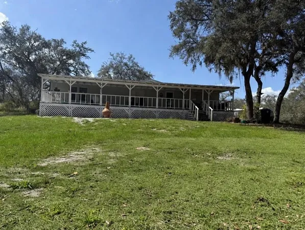 a view of a yard in front of a house with large trees