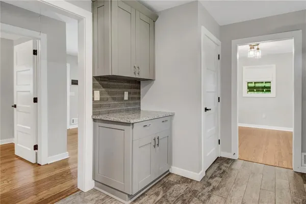 a kitchen with white cabinets and wooden floor