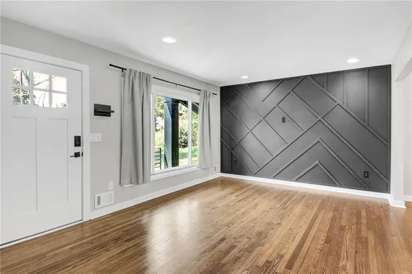 a view of an empty room with wooden floor and a window