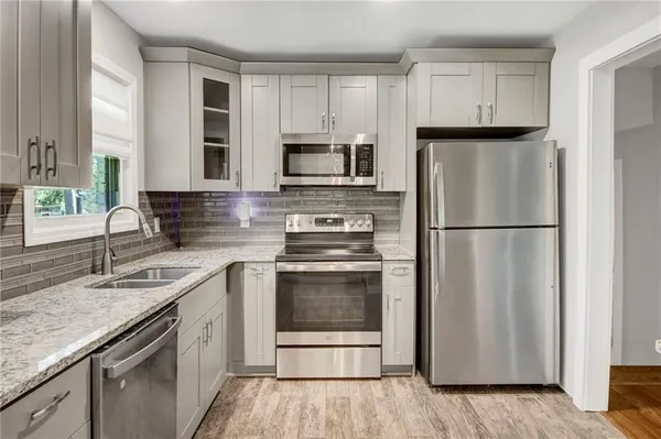 a kitchen with granite countertop a refrigerator stove and sink