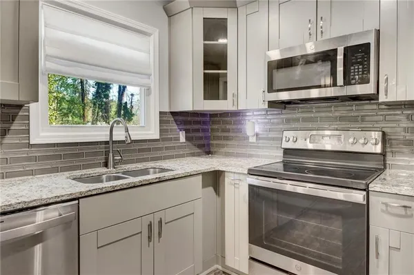 a kitchen with stainless steel appliances granite countertop a stove microwave and cabinets