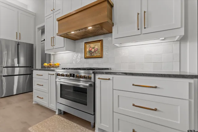 a kitchen with stainless steel appliances granite countertop white cabinets and a refrigerator