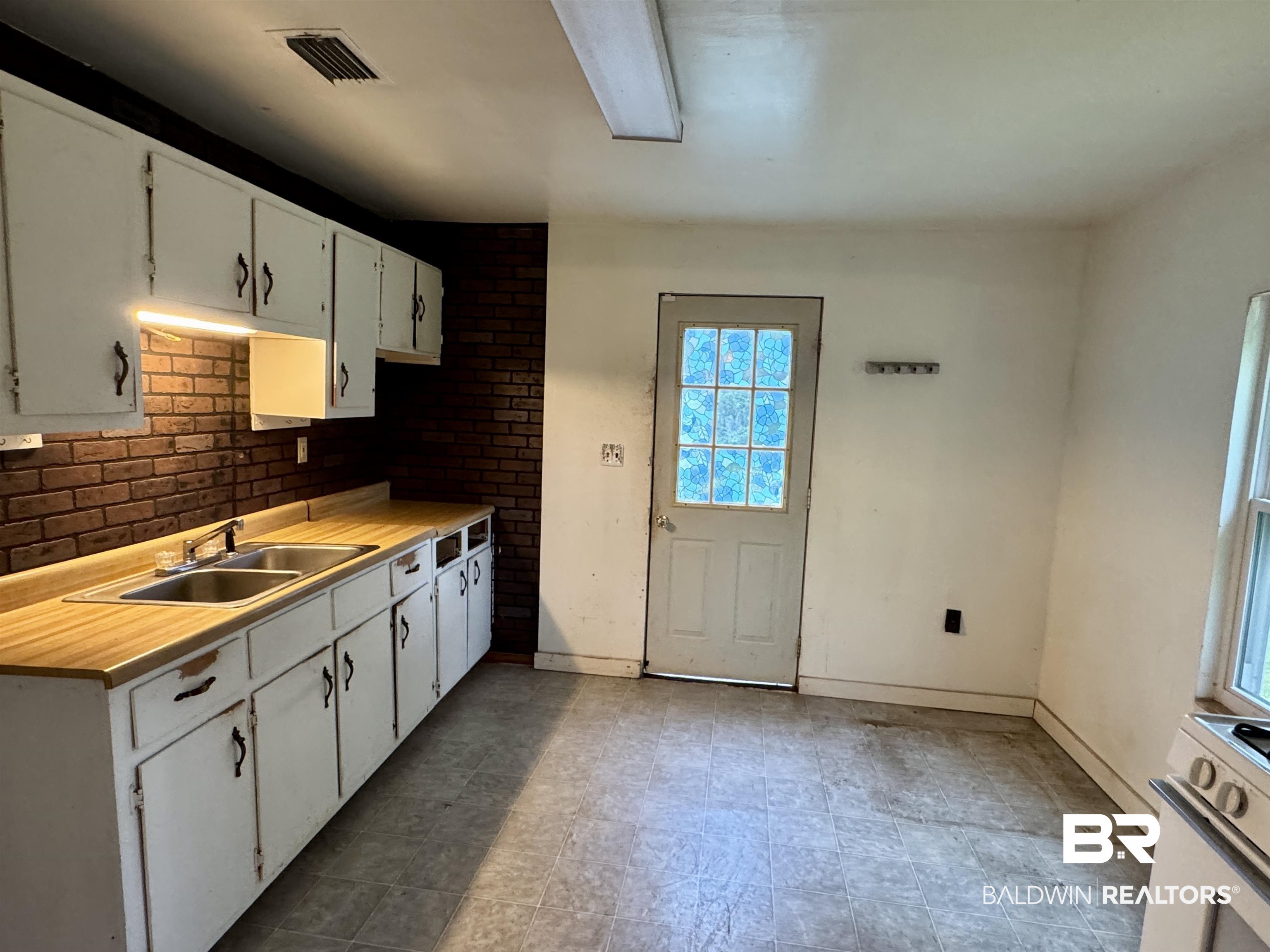42186 Nicholsville Road Bay Minette, AL 36507 - Photo 5 of 10 Kitchen with a sink, light countertops, white cabinetry, and baseboards