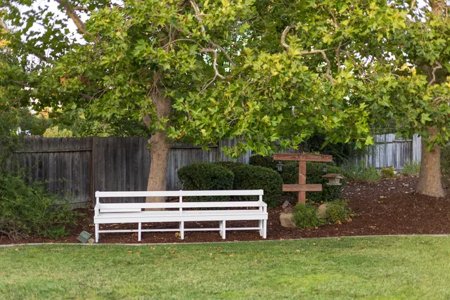 a view of a wooden bench sitting in a yard with wooden fence