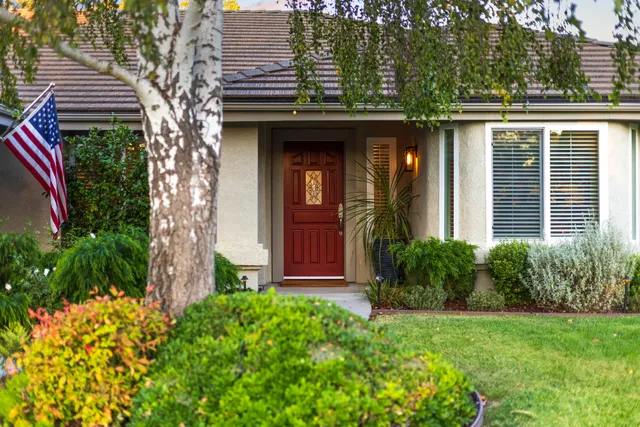a view of a house with brick walls and a yard with plants